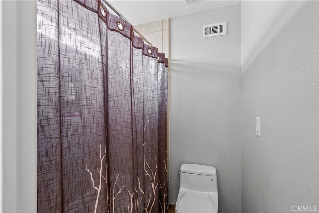 25726 Emerson Lane Stevenson Ranch, CA 91381 - Photo 29 of 45 a bathroom with a toilet and a shower curtain