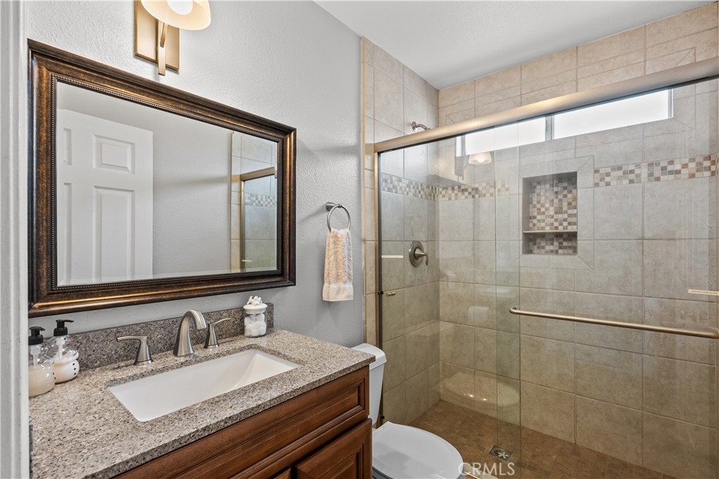 25726 Emerson Lane Stevenson Ranch, CA 91381 - Photo 34 of 45 a bathroom with a granite countertop sink toilet a mirror and shower