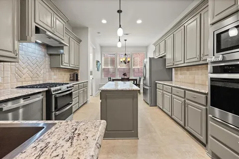 a kitchen with stainless steel appliances kitchen island granite countertop a stove top oven a sink dishwasher a dining table and chairs with wooden floor