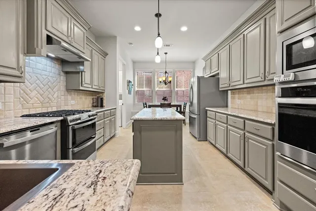 a kitchen with stainless steel appliances kitchen island granite countertop a stove top oven a sink dishwasher a dining table and chairs with wooden floor