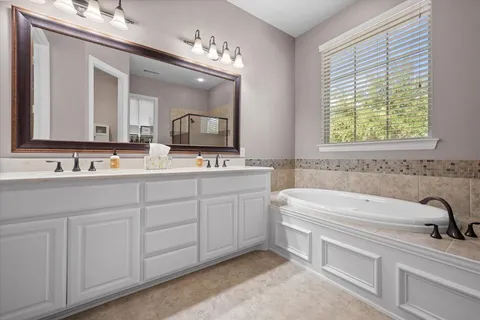 a spacious bathroom with a double vanity sink mirror and bathtub