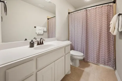 a bathroom with a sink a toilet and shower curtain