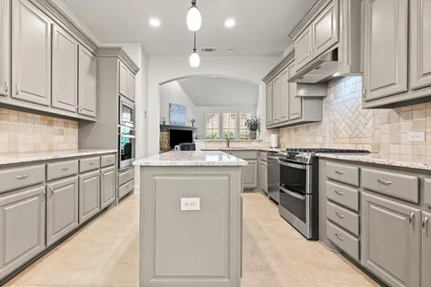 a kitchen with kitchen island granite countertop a sink cabinets stainless steel appliances and a counter space