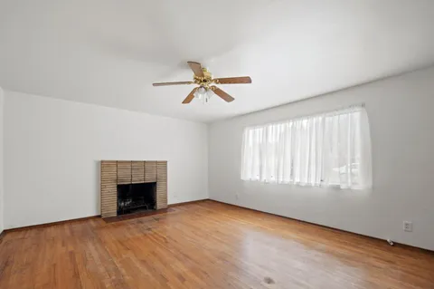 an empty room with ceiling fan and windows