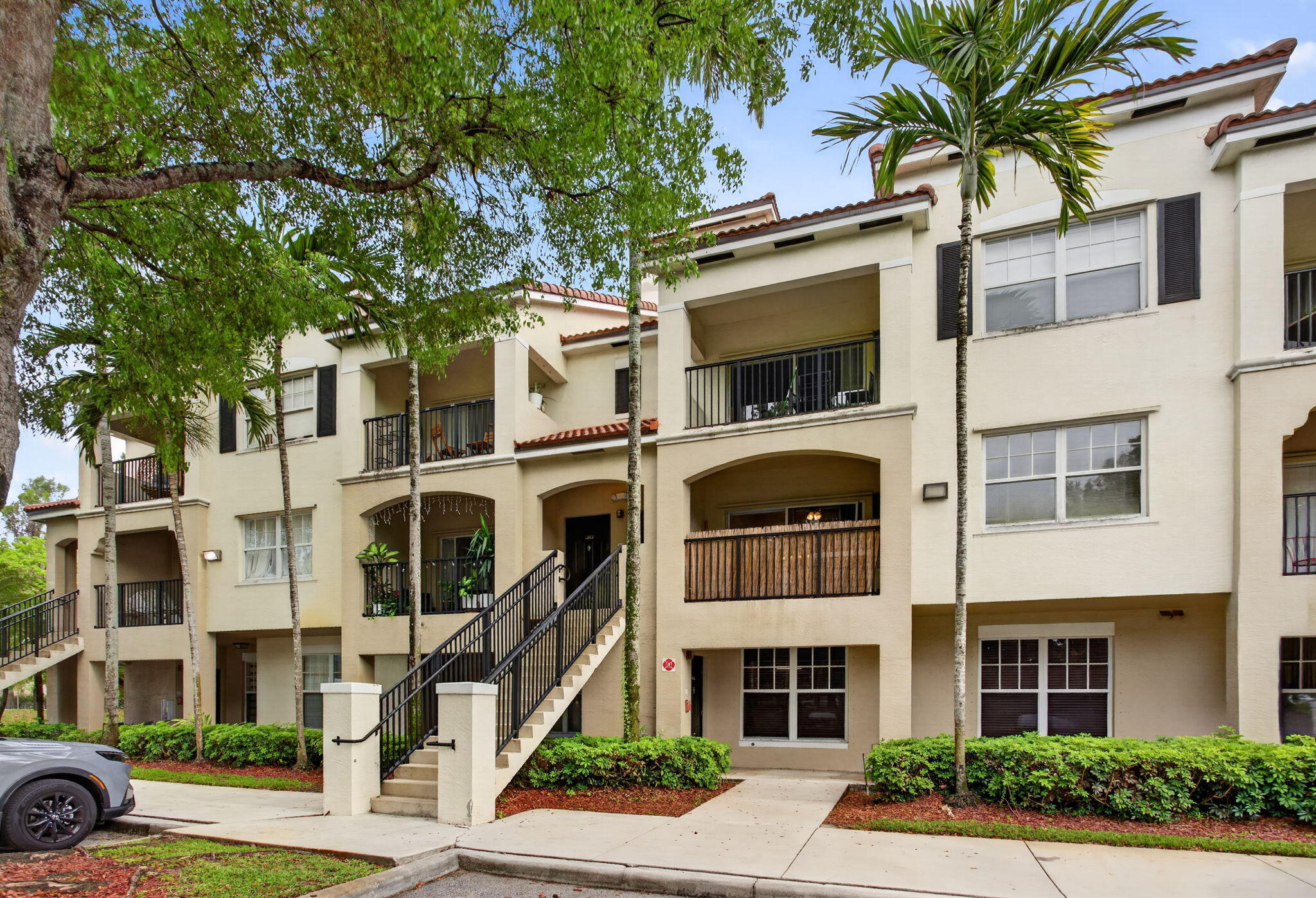 a front view of a multi story residential apartment building with yard and parking space