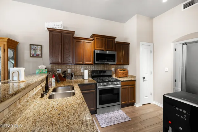 a kitchen with stainless steel appliances granite countertop a sink stove and refrigerator