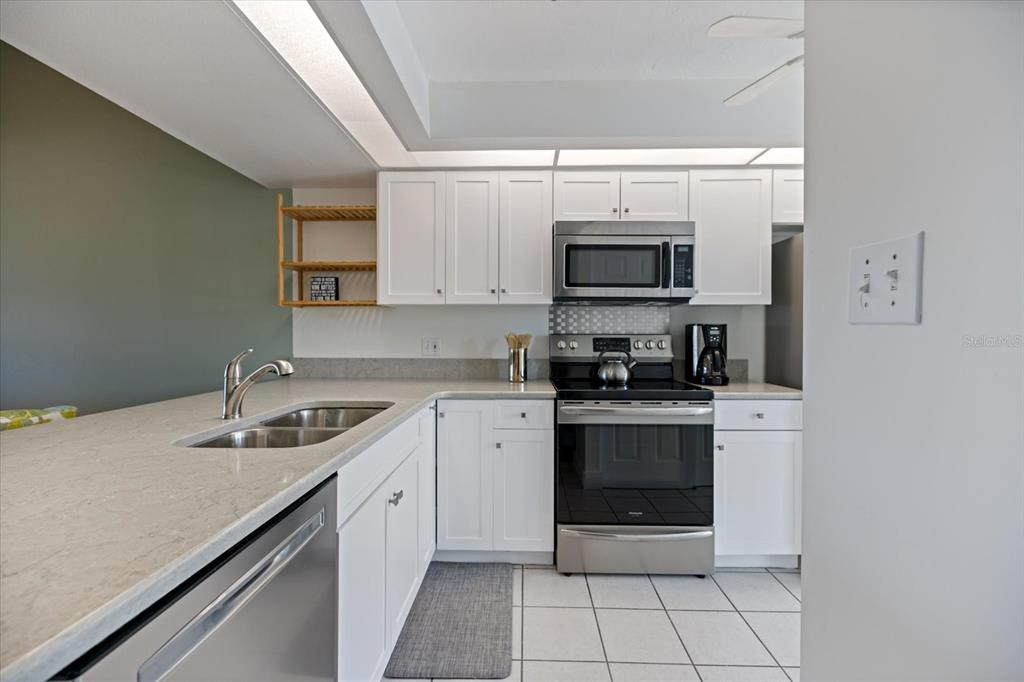 841 Waterside Drive, Unit 202 Venice, FL 34285 - Photo 6 of 43 a kitchen with stainless steel appliances granite countertop a sink stove and microwave