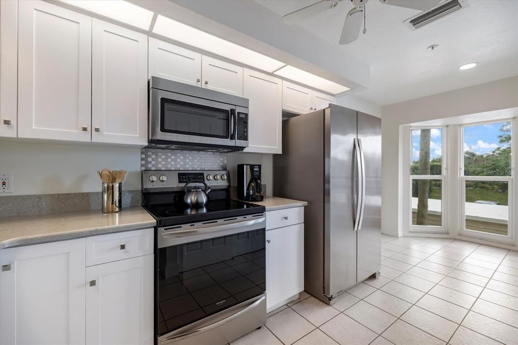841 Waterside Drive, Unit 202 Venice, FL 34285 - Photo 7 of 43 a kitchen with stainless steel appliances granite countertop a stove a refrigerator and a sink