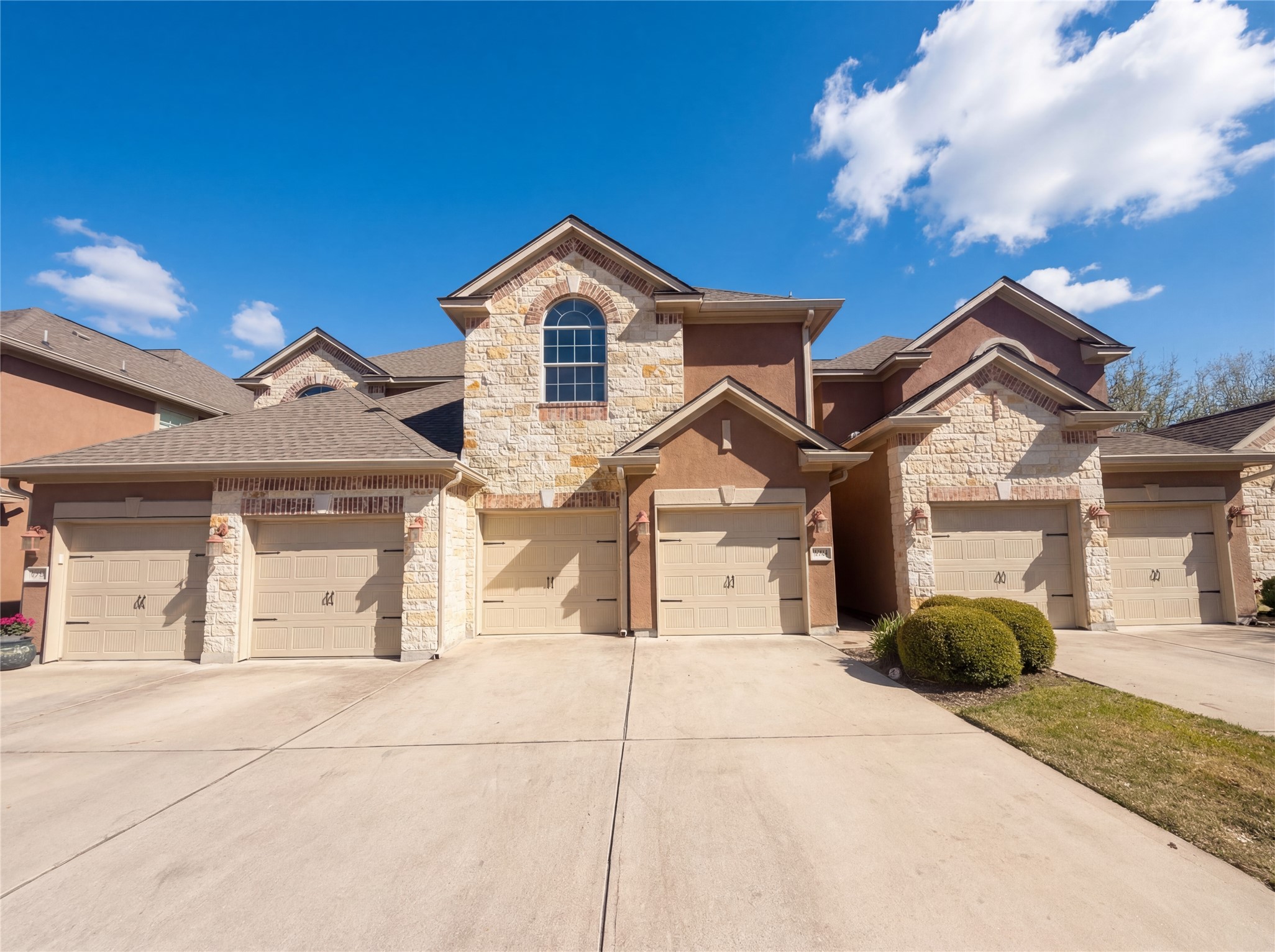 View of front of home with stone siding, driveway, and a shingled roof