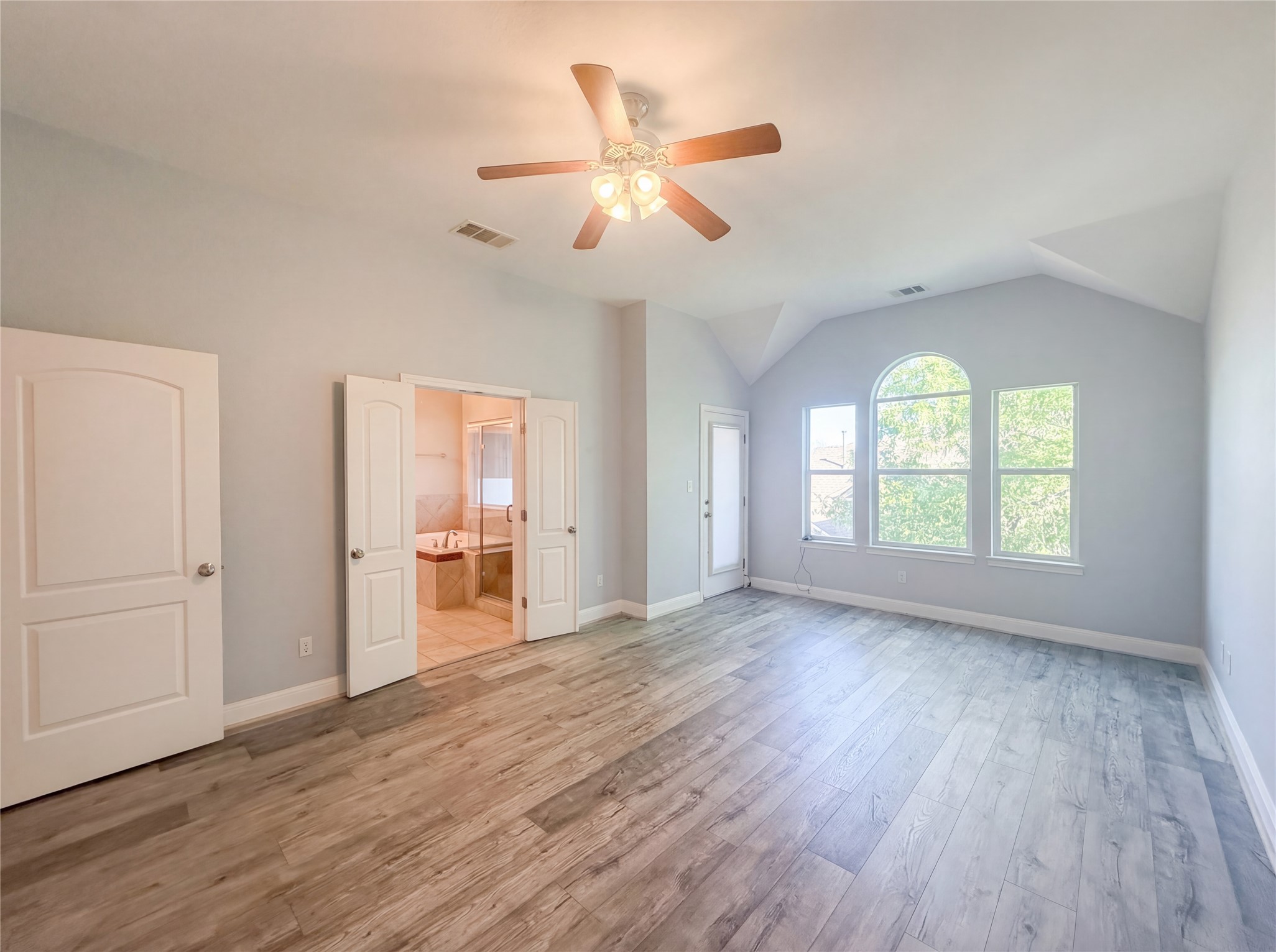 104 Perpetuation Drive Austin, TX 78734 - Photo 4 of 29 Unfurnished bedroom featuring light wood-style flooring, ceiling fan, vaulted ceiling, and ensuite bathroom