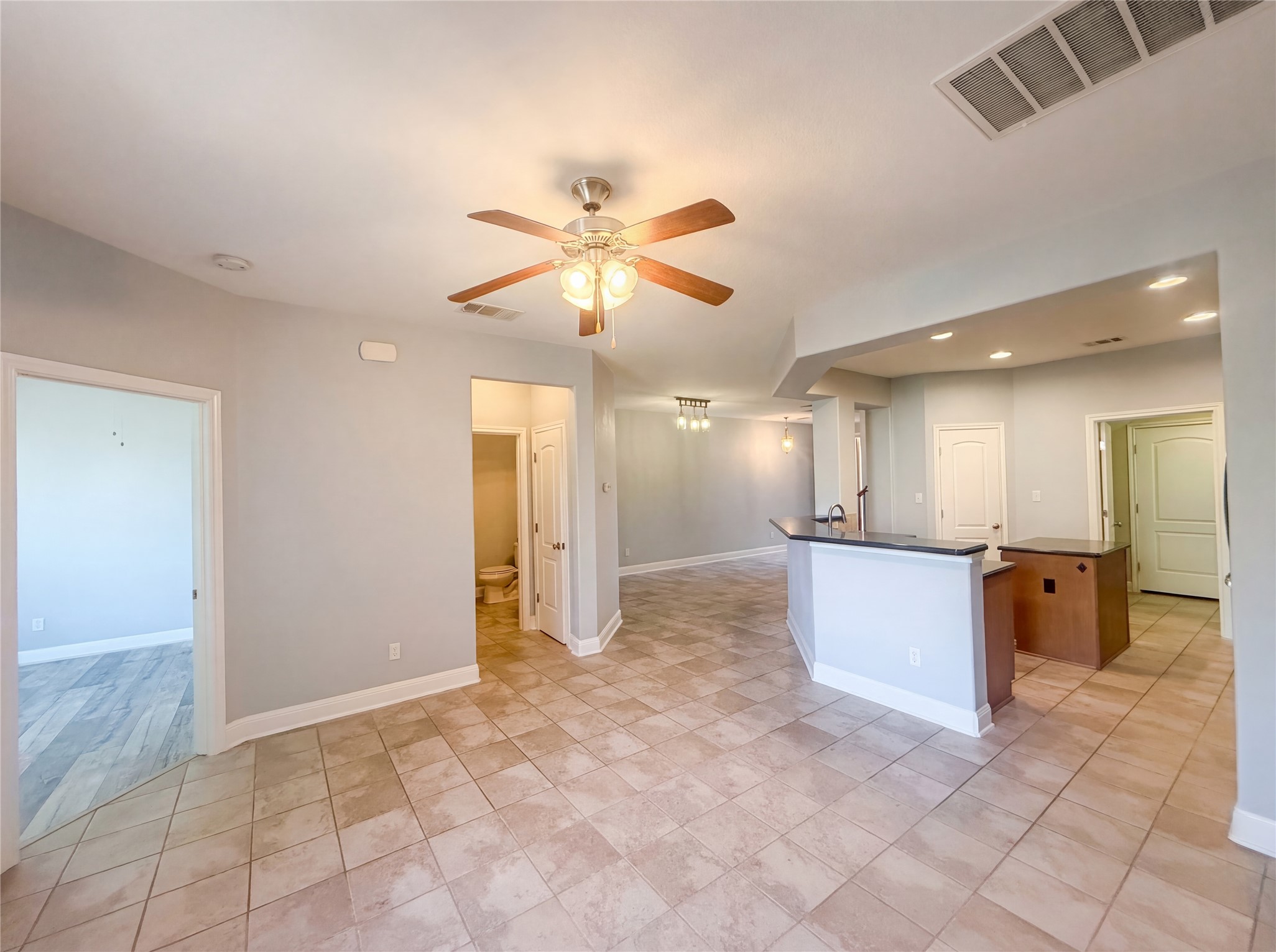 104 Perpetuation Drive Austin, TX 78734 - Photo 6 of 29 Kitchen with dark countertops, an island with sink, a ceiling fan, and recessed lighting