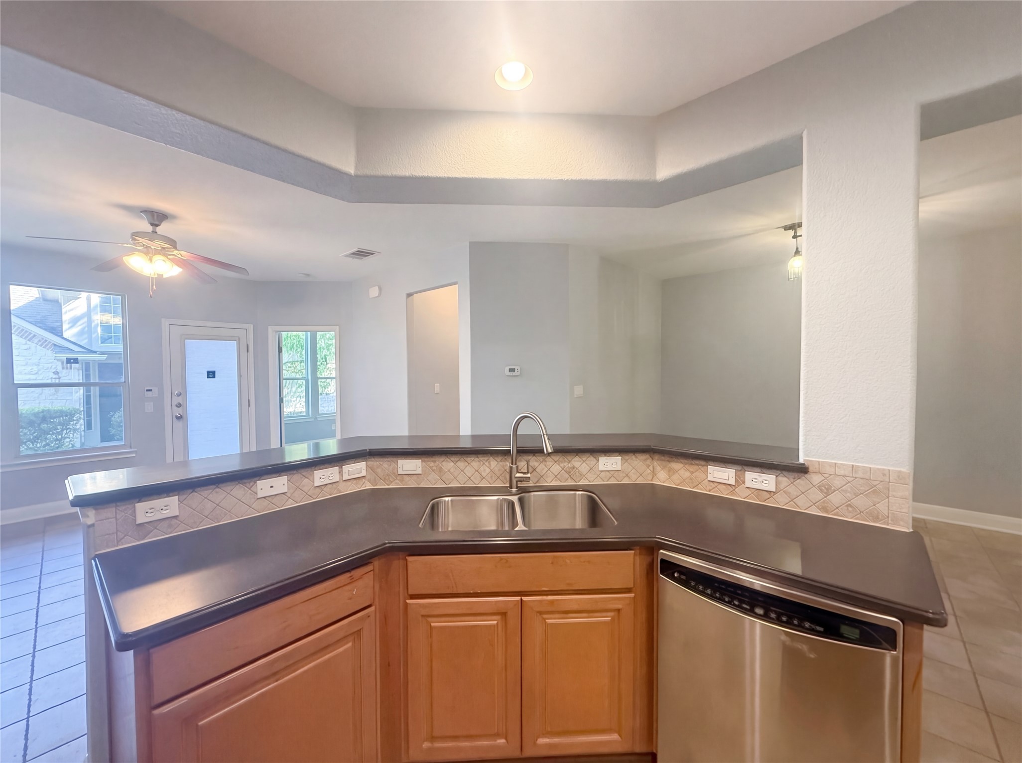 104 Perpetuation Drive Austin, TX 78734 - Photo 28 of 29 Kitchen with light tile patterned flooring, stainless steel dishwasher, a ceiling fan, dark countertops, and open floor plan