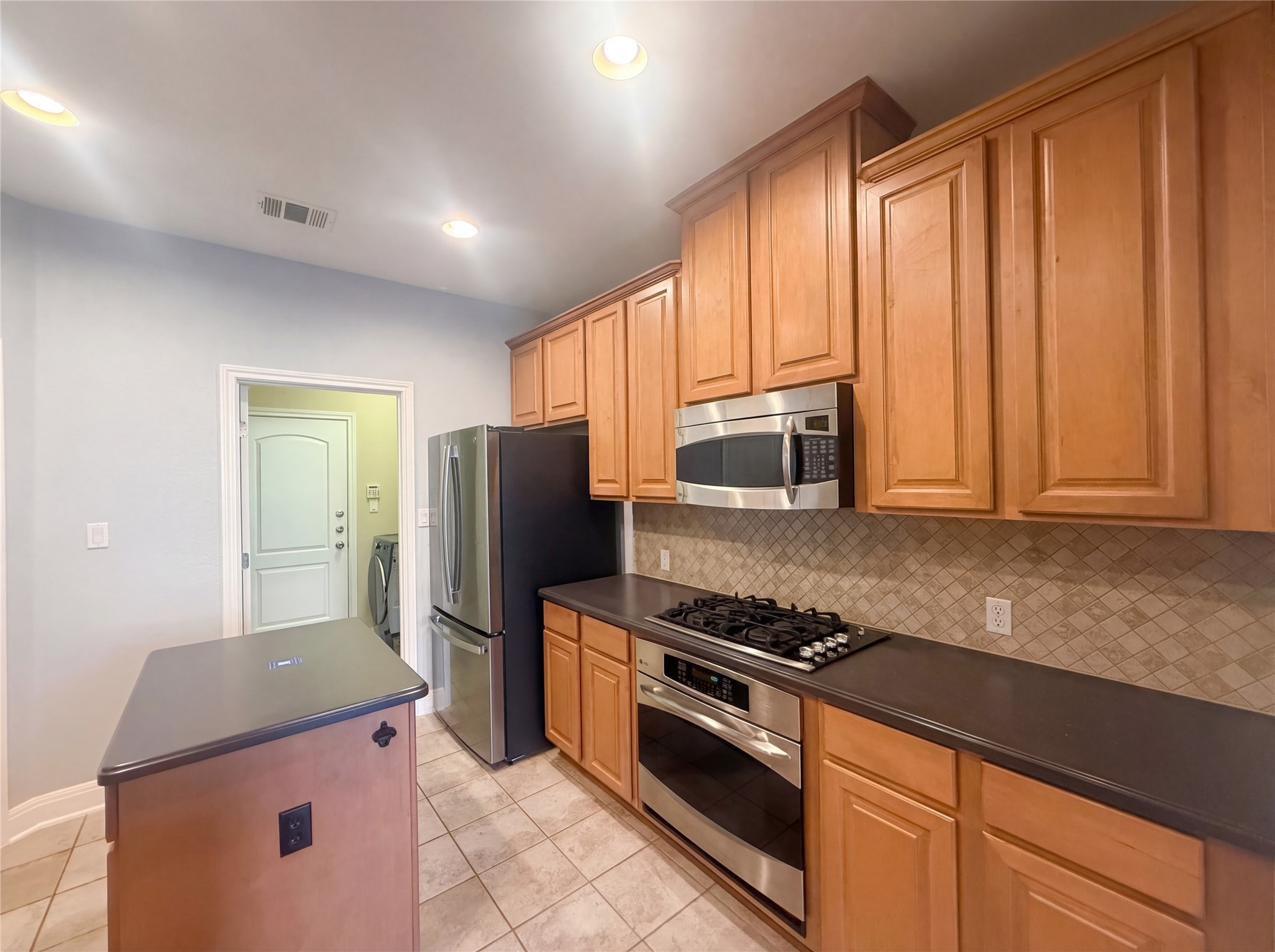 104 Perpetuation Drive Austin, TX 78734 - Photo 8 of 29 Kitchen featuring stainless steel appliances, dark countertops, a kitchen island, light tile patterned flooring, and recessed lighting