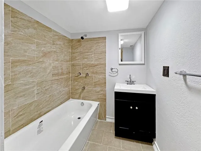 a bathroom with a tub sink shower and mirror