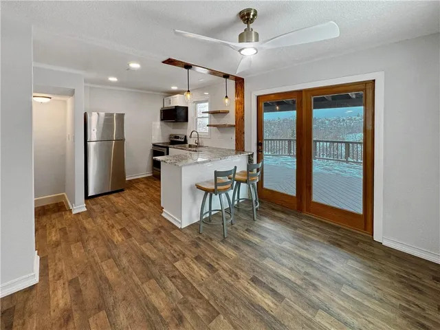 a kitchen with stainless steel appliances granite countertop a refrigerator a stove top oven a sink dishwasher a dining table and chairs with wooden floor