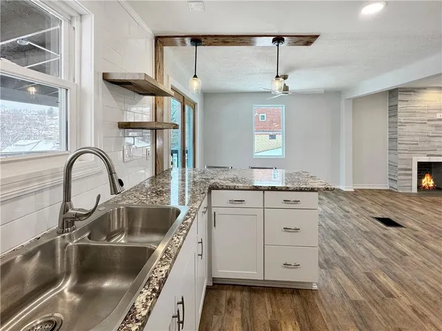 a kitchen with granite countertop a sink stainless steel appliances and living room view