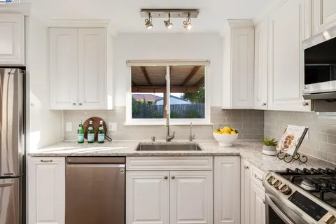 a kitchen with stainless steel appliances a stove a sink and white cabinets