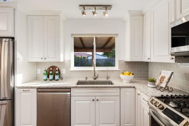 a kitchen with stainless steel appliances a stove a sink and white cabinets