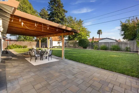 a view of a patio with a table chairs and a yard