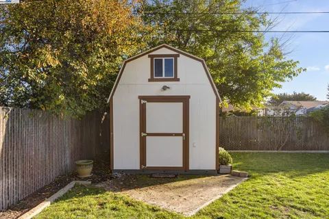a view of a small house with a small yard and wooden fence