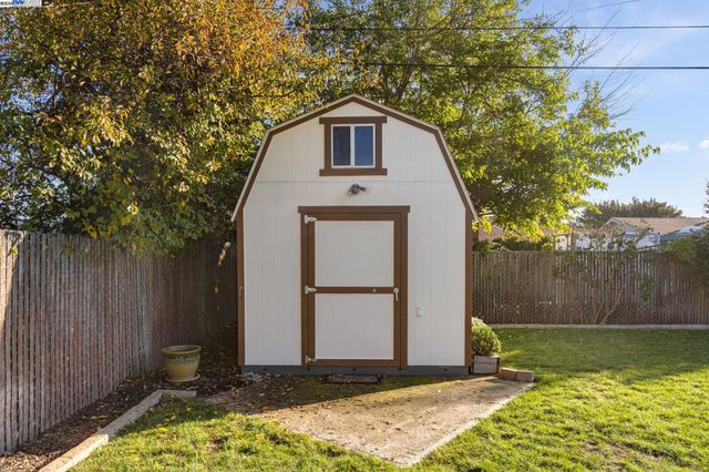 a view of a small house with a small yard and wooden fence