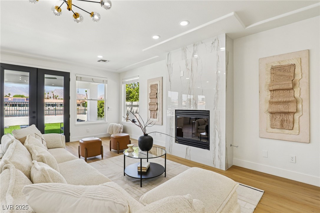 2469 Sun Reef Road Las Vegas, NV 89128 - Photo 15 of 93 Living room with wood finished floors, a premium fireplace, recessed lighting, french doors, and a chandelier