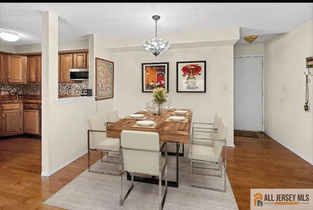a dining room with wooden floor a chandelier a wooden table and chairs