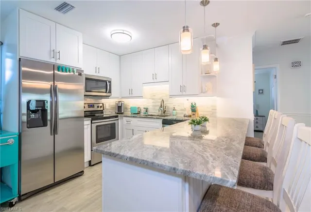 a kitchen with granite countertop a refrigerator a sink a stove a dining table and chairs