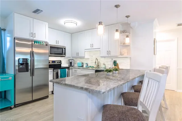 a kitchen with stainless steel appliances granite countertop a sink refrigerator and microwave