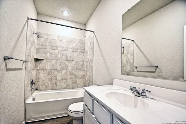 a bathroom with a bathtub shower sink vanity mirror and toilet