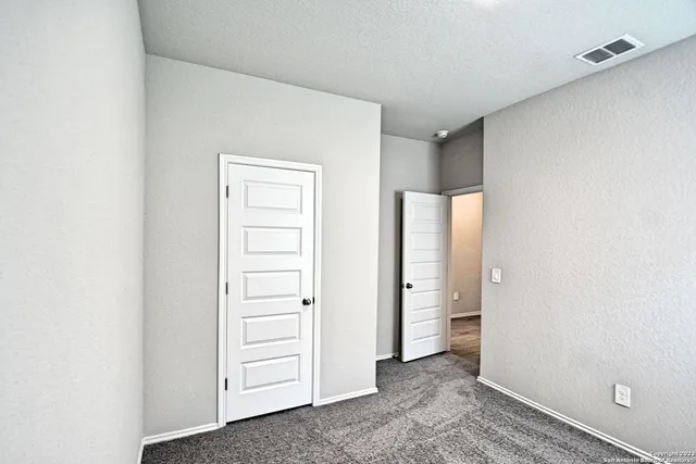 a view of an empty room with closet and a window