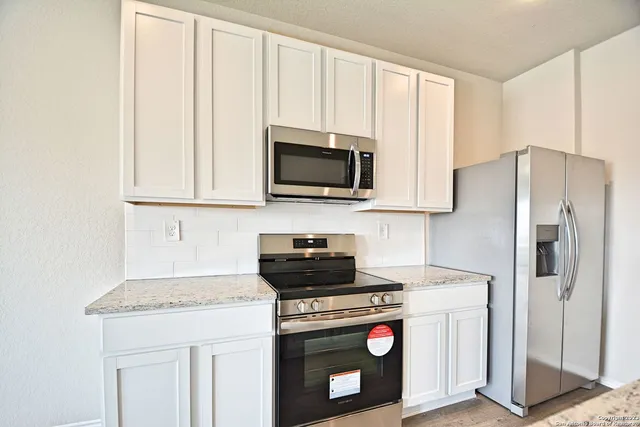 a kitchen with stainless steel appliances granite countertop a stove a refrigerator and a microwave