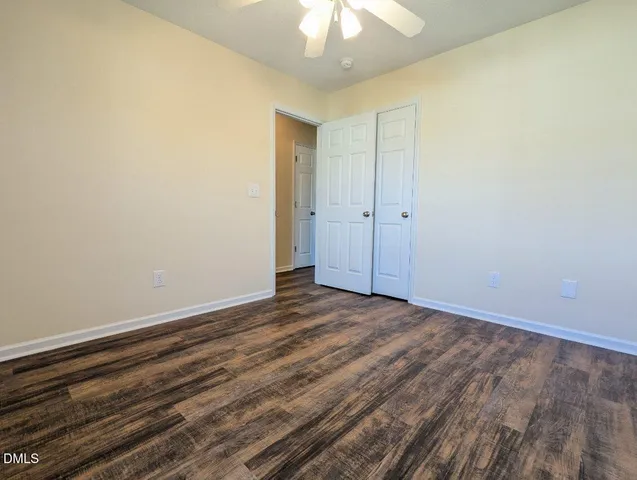 a view of an empty room and chandelier fan