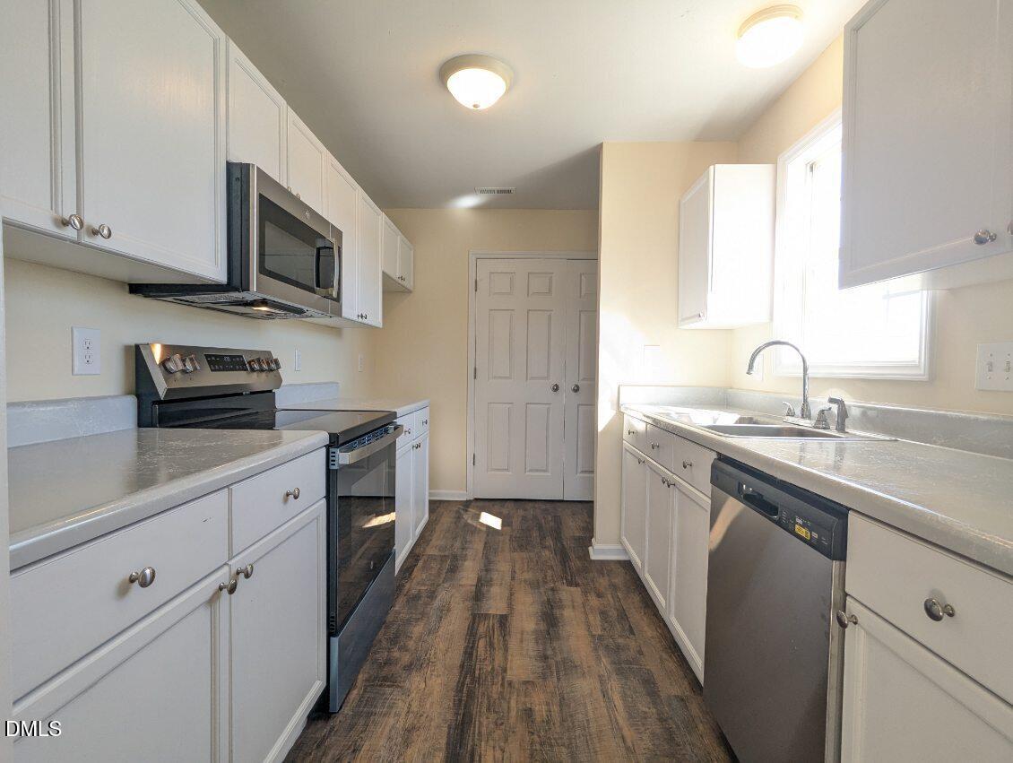 100 Reebe Circle Selma, NC 27576 - Photo 9 of 19 a kitchen with stainless steel appliances a sink dishwasher a stove top oven a refrigerator with wooden floors and cabinets