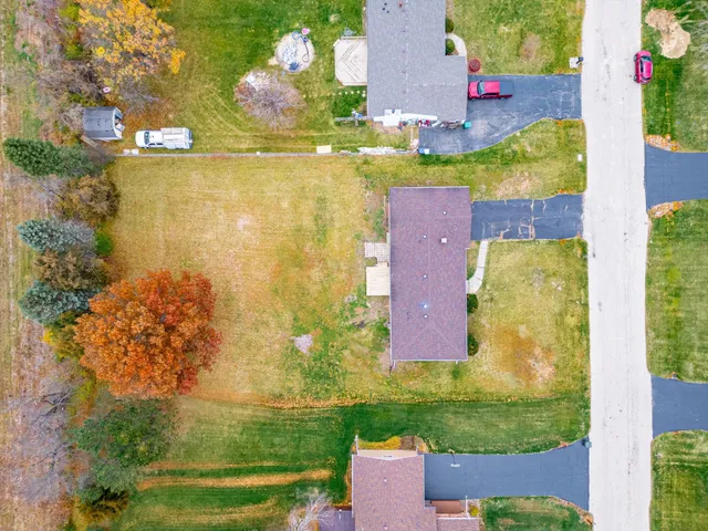 an aerial view of residential houses with outdoor space and trees all around