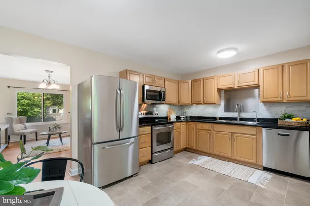 a kitchen with stainless steel appliances granite countertop a refrigerator a stove a sink and a microwave