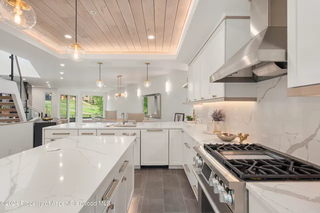 a large kitchen with stainless steel appliances a sink a stove and cabinets