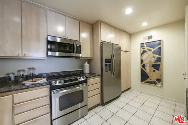a kitchen with stainless steel appliances granite countertop a refrigerator and a stove top oven