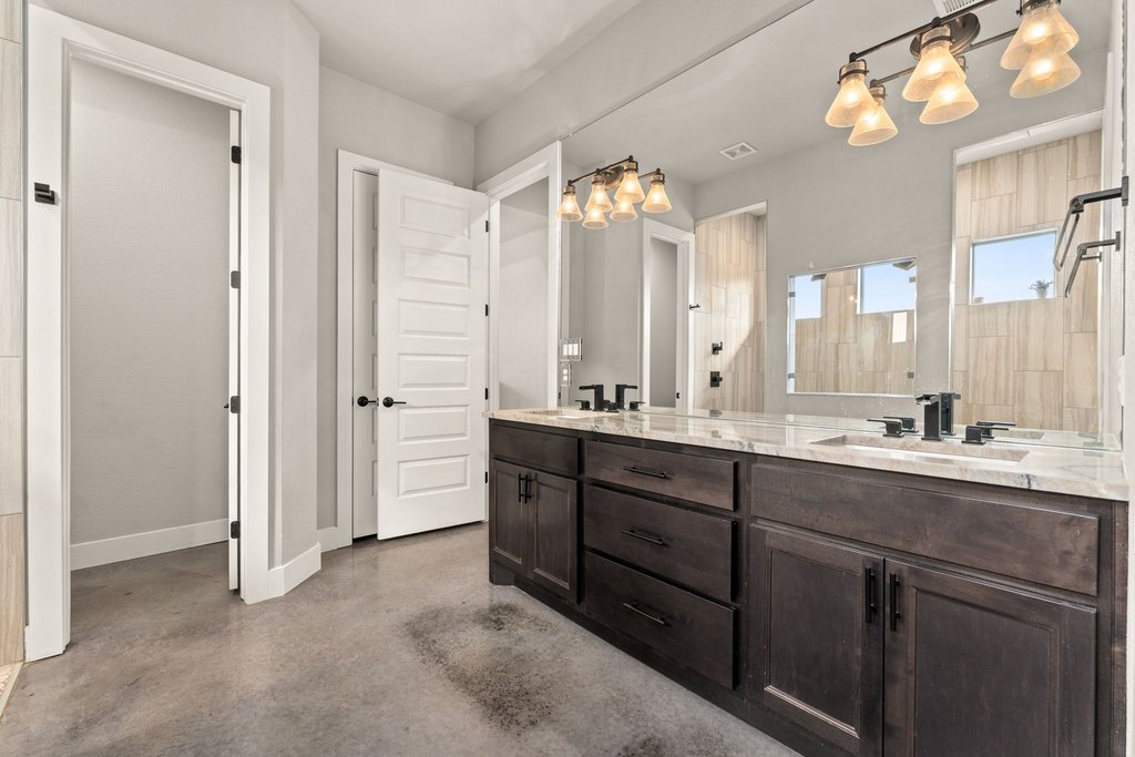 3830 Outback Trail Spicewood, TX 78669 - Photo 23 of 40 a bathroom with double vanity sinks a vanity a lamp and a shower