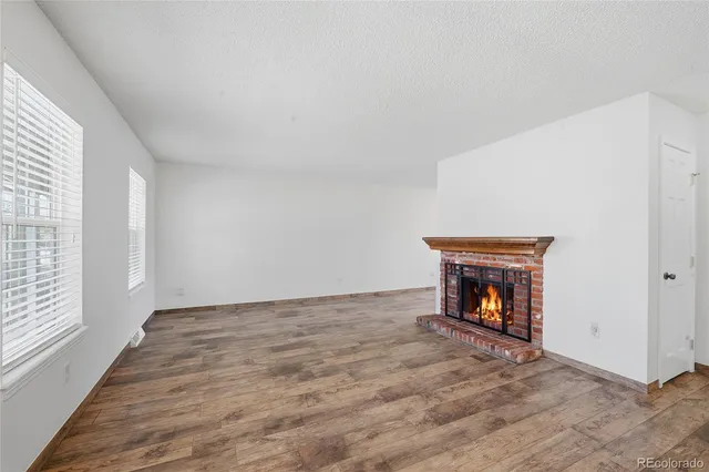 a view of an empty room with window and a fireplace