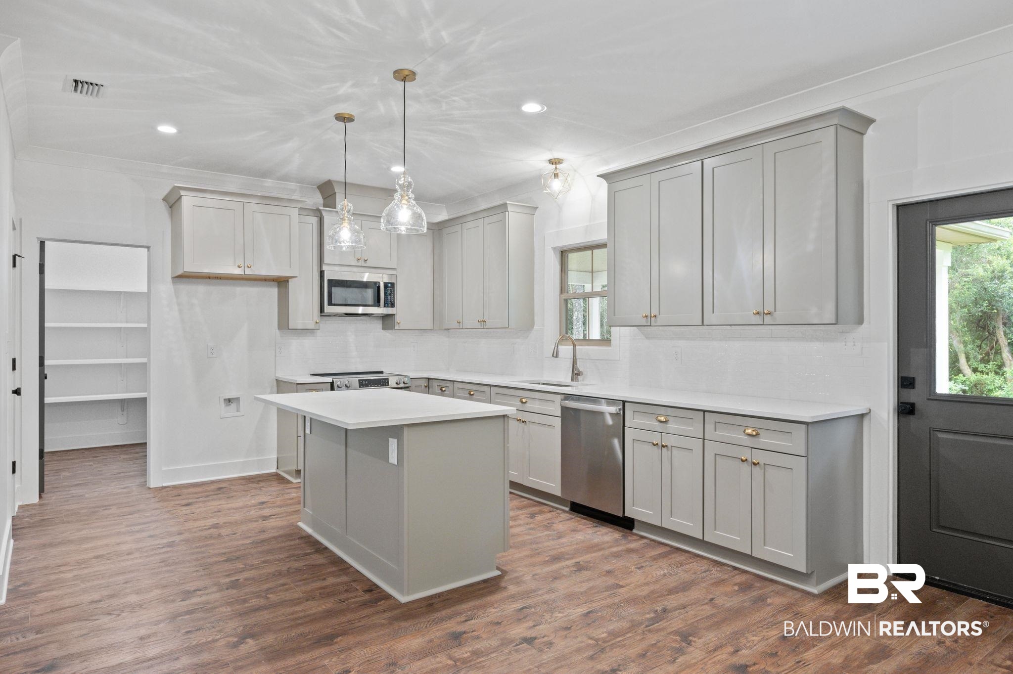 12412 Mannich Lane Foley, AL 36535 - Photo 7 of 23 Kitchen with appliances with stainless steel finishes, a kitchen island, gray cabinets, and dark hardwood / wood-style floors