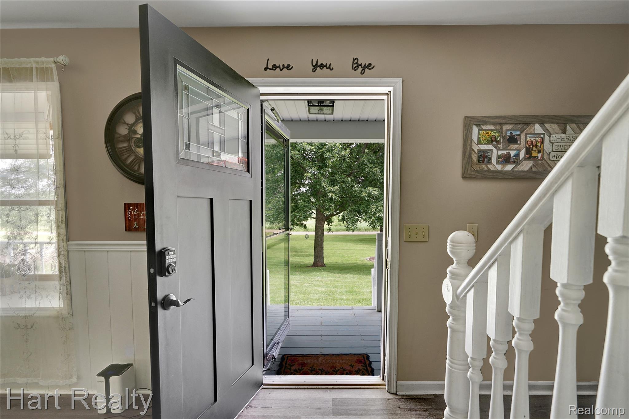 7167 Brown School Road North Branch, MI 48461 - Photo 6 of 51 Entryway featuring a dark paneled door with decorative glass inserts, a white staircase with turned newel posts, wainscoting, and wood-finish flooring