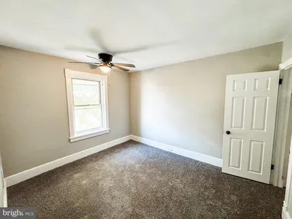 an empty room with windows and ceiling fan