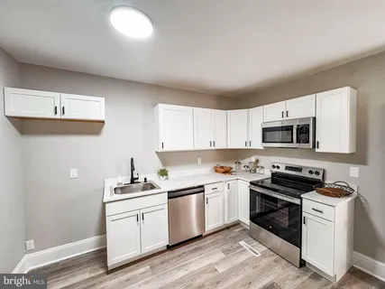 a kitchen with white cabinets stainless steel appliances and sink