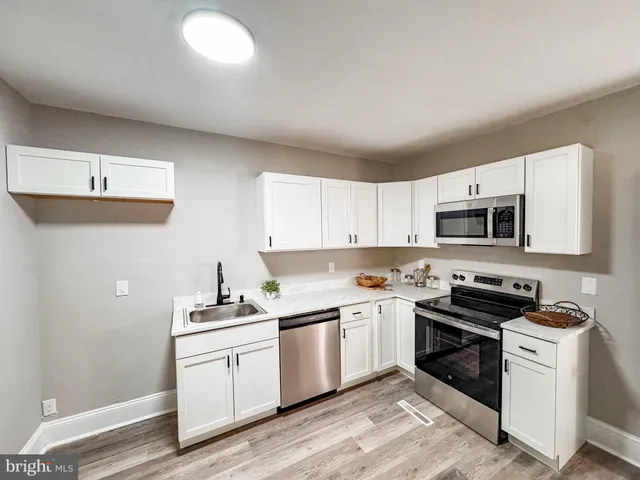 a kitchen with white cabinets stainless steel appliances and sink