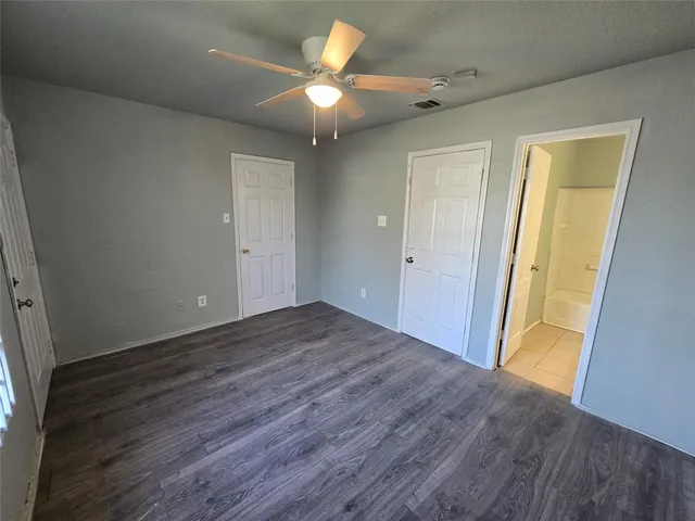 an empty room with wooden floor and a ceiling fan