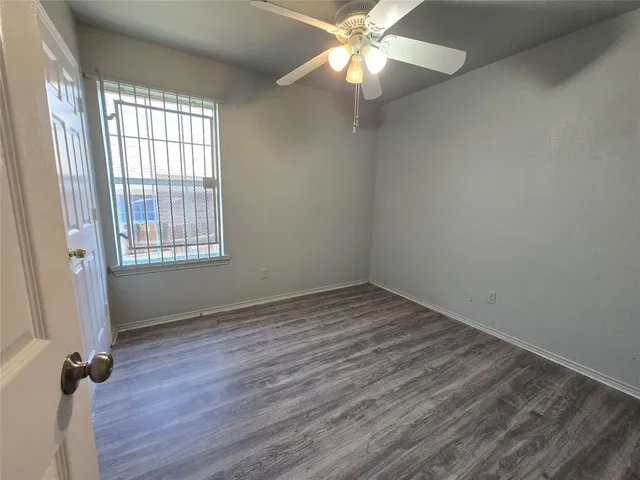 an empty room with wooden floor fan and windows