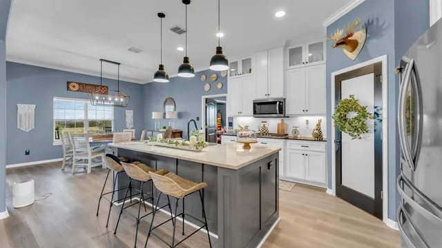 a kitchen with kitchen island a dining table chairs sink and stove