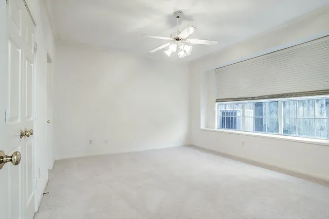 an empty room with a chandelier fan and closet area