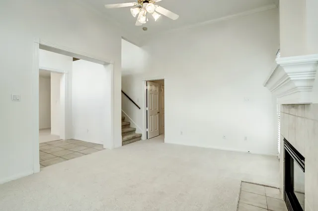 an empty room with a chandelier fan and windows